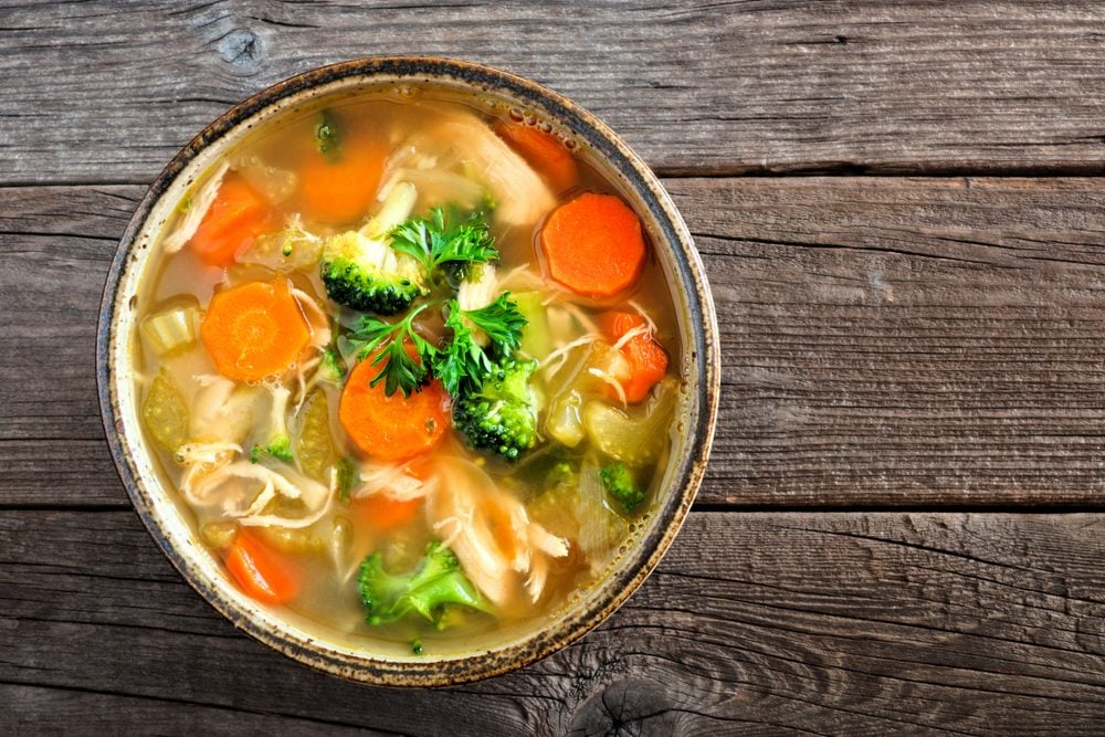 bowl of chicken soup with broccoli and carrots