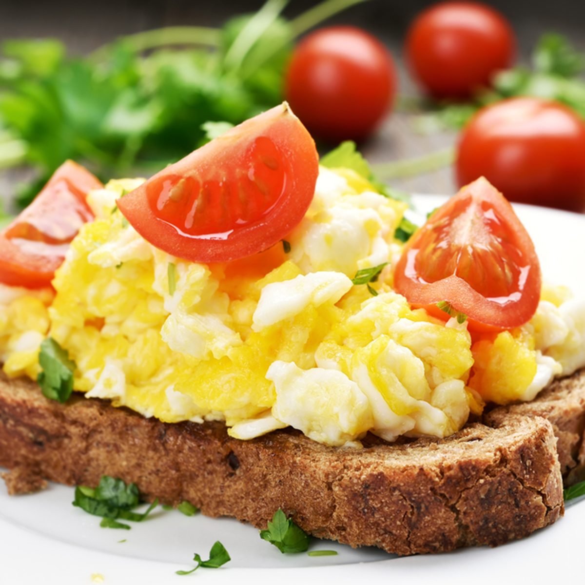 Breakfast scrambled eggs and tomato slices on bread|