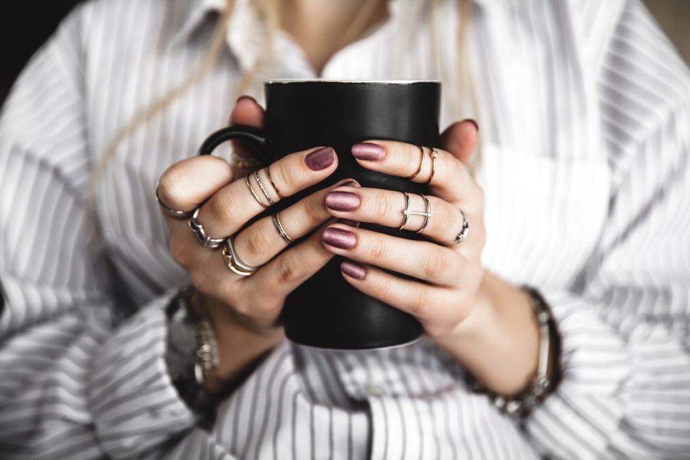 Female hands holding a white cup of tea, burgundy manicure|Cup of hot sage herbal tea|close-up of three hands holding small cups of tea