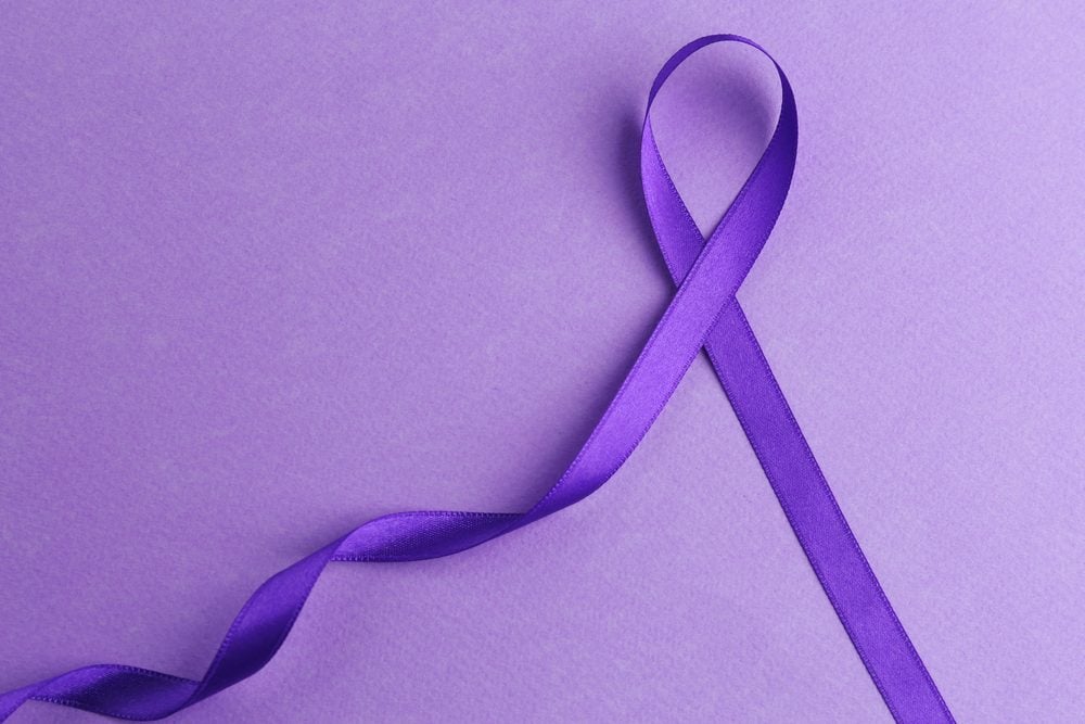 Violet ribbon on color background. Family violence, Alzheimer disease and pancreas cancer concept