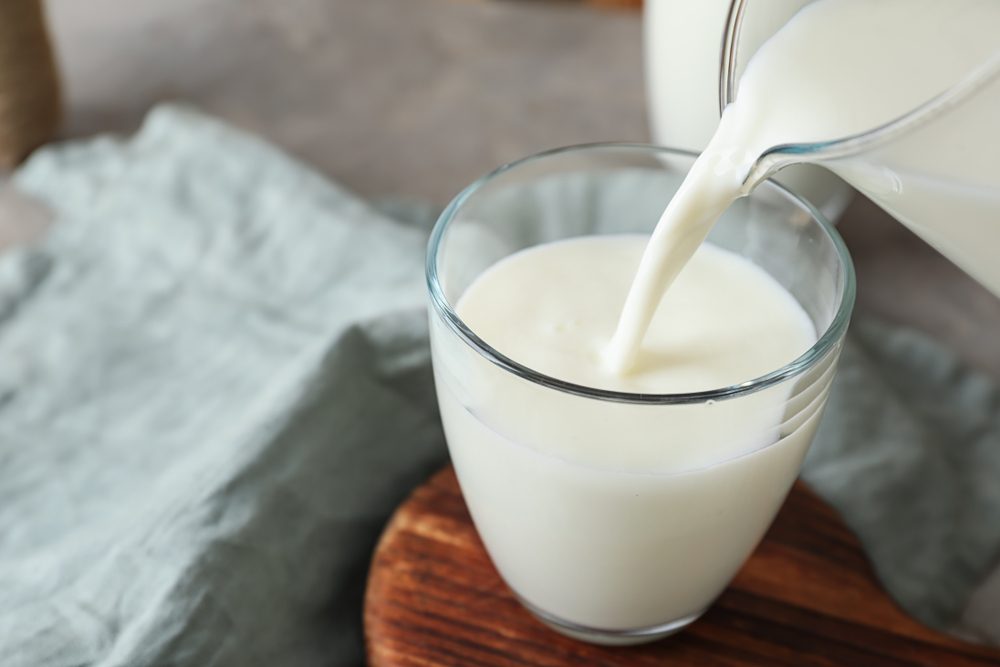 Pouring of milk into glass on table