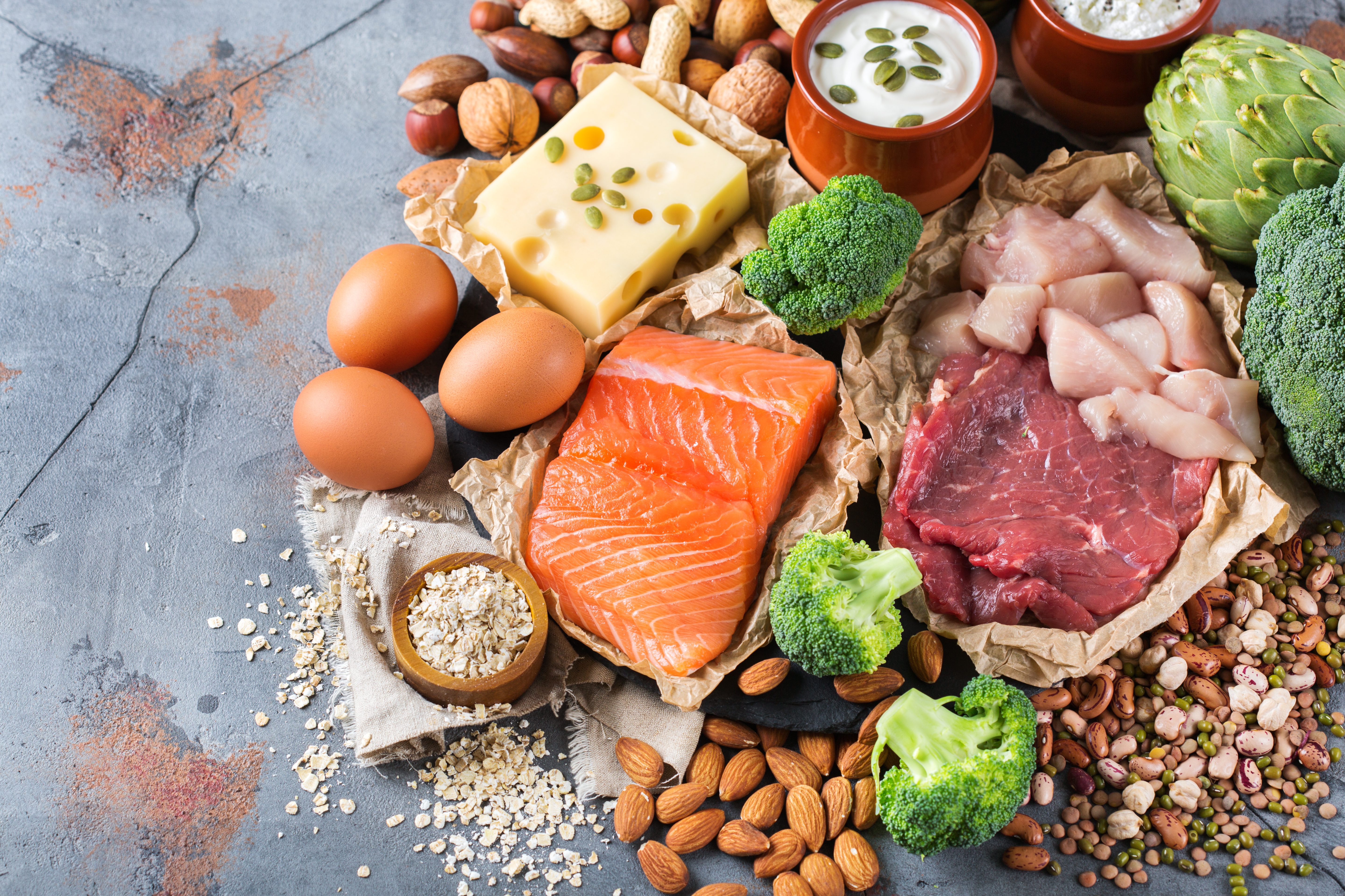 Assortment of healthy protein source and body building food. Meat beef salmon chicken breast eggs dairy products cheese yogurt beans artichokes broccoli nuts oat meal. Top view flat lay