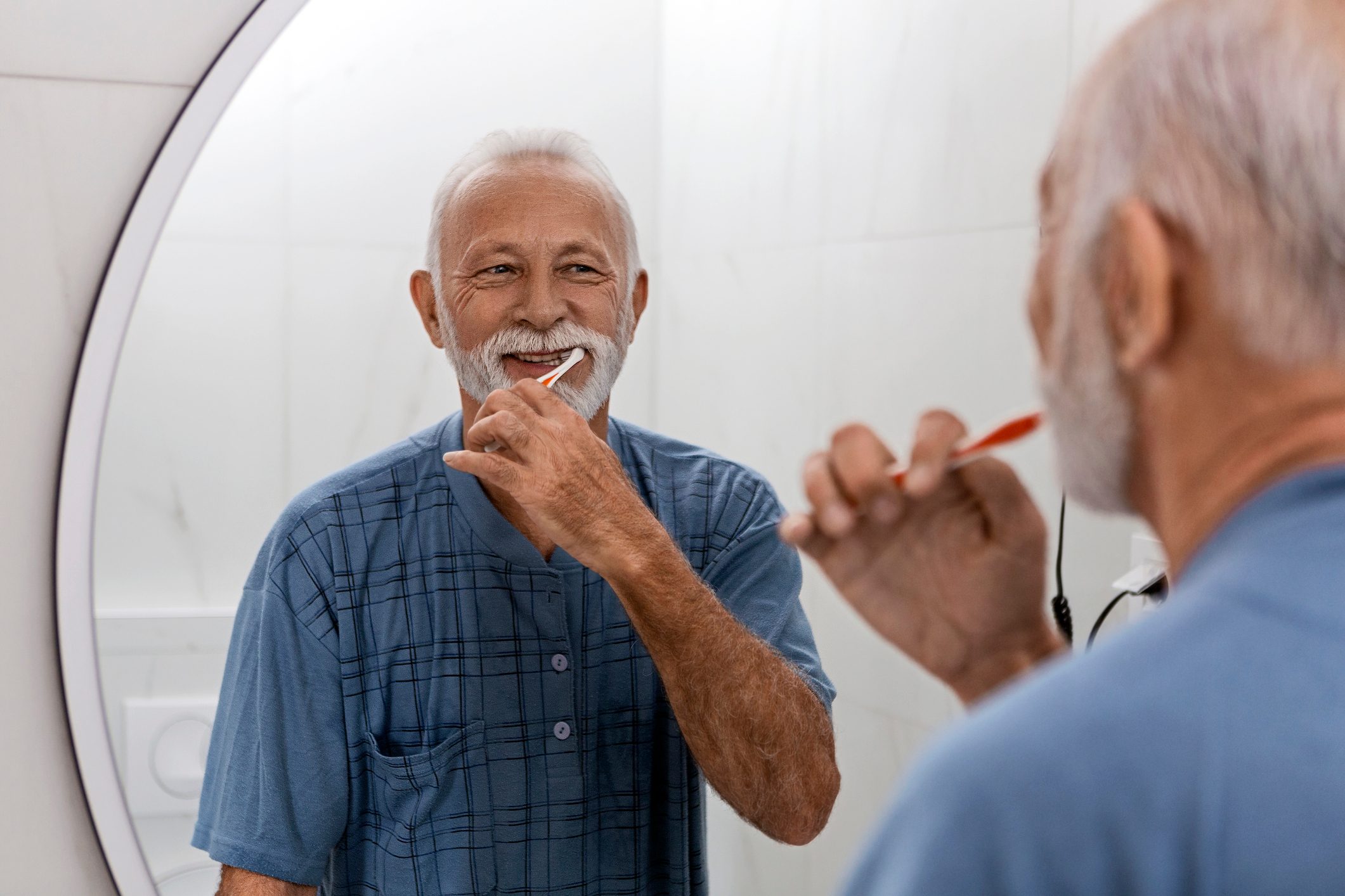 older man brushing his teeth in bathroom mirror|toothbrush|lips|protection|lemons|ice|wine|water