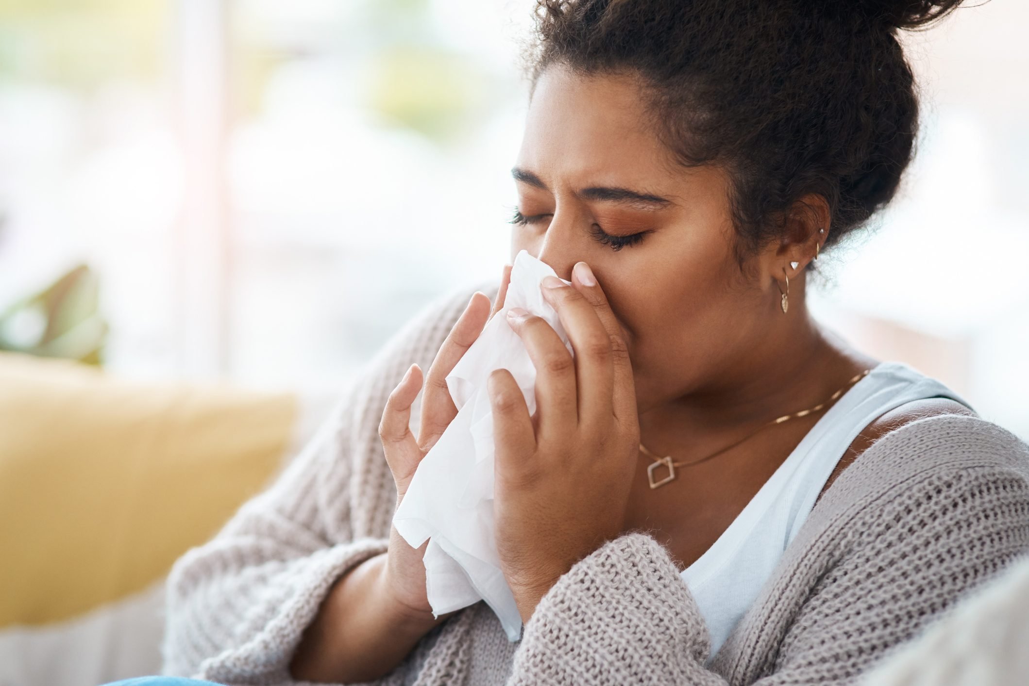 woman sneezing blowing her nose into a tissue|