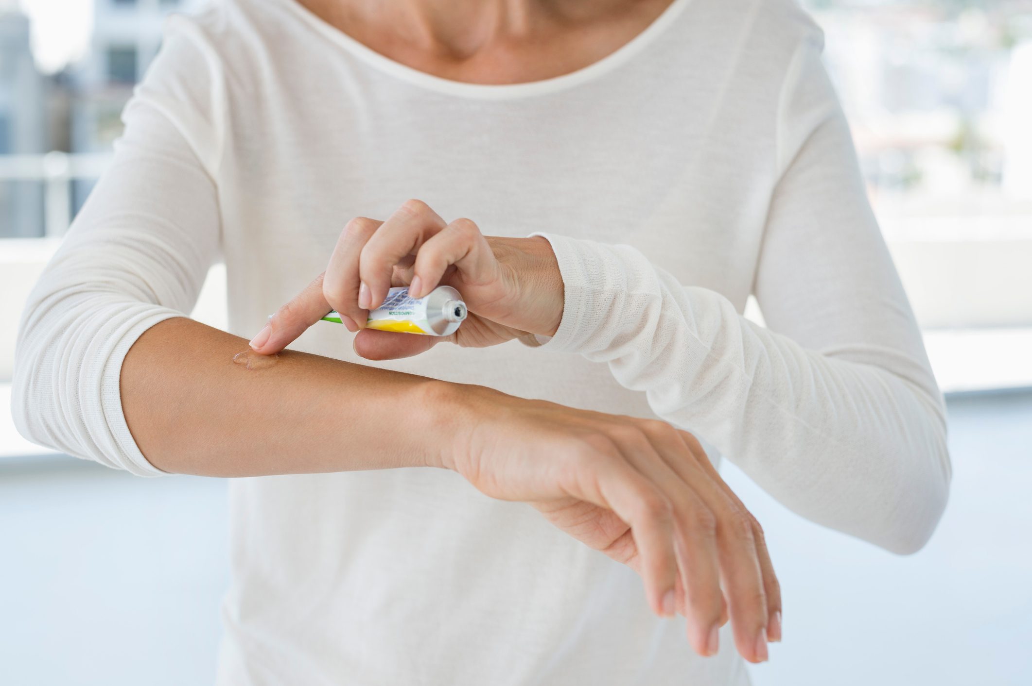 Woman applying ointment on arm