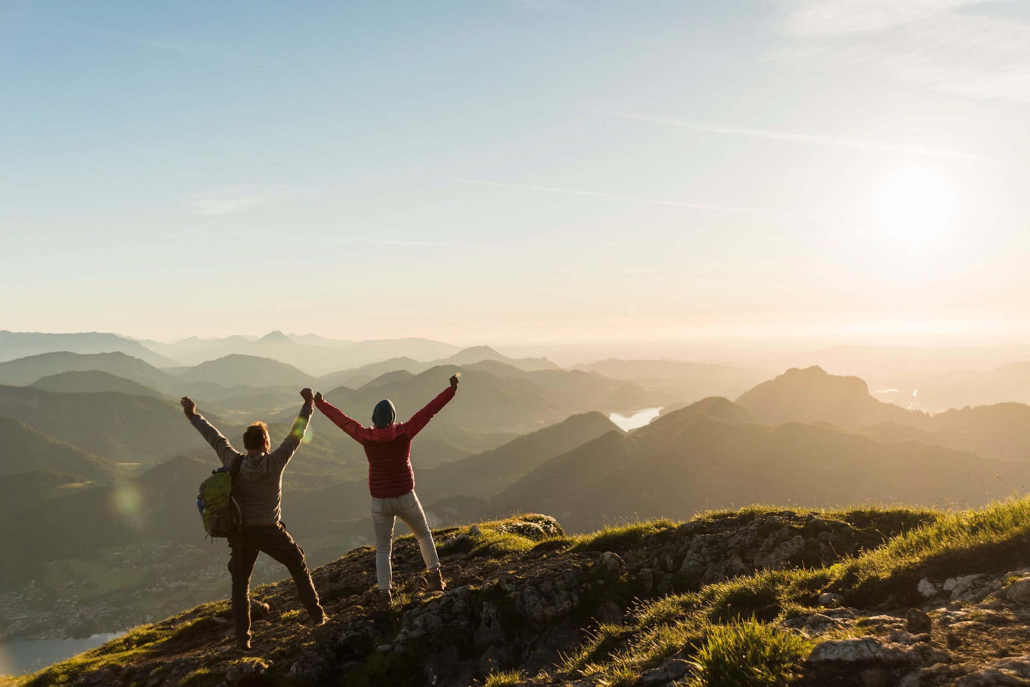 couple on top of mountain with hands up