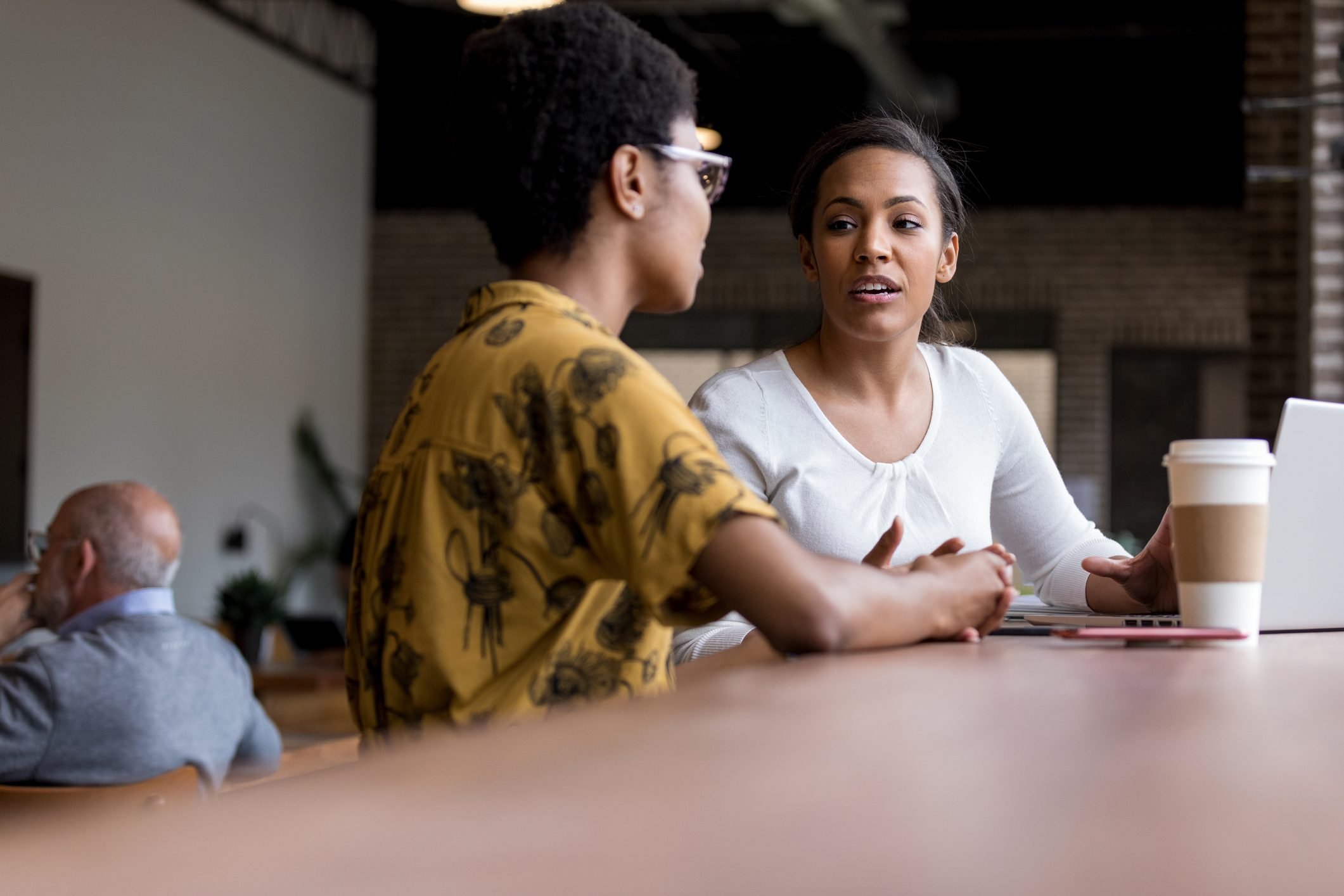 Women talk while having coffee together|