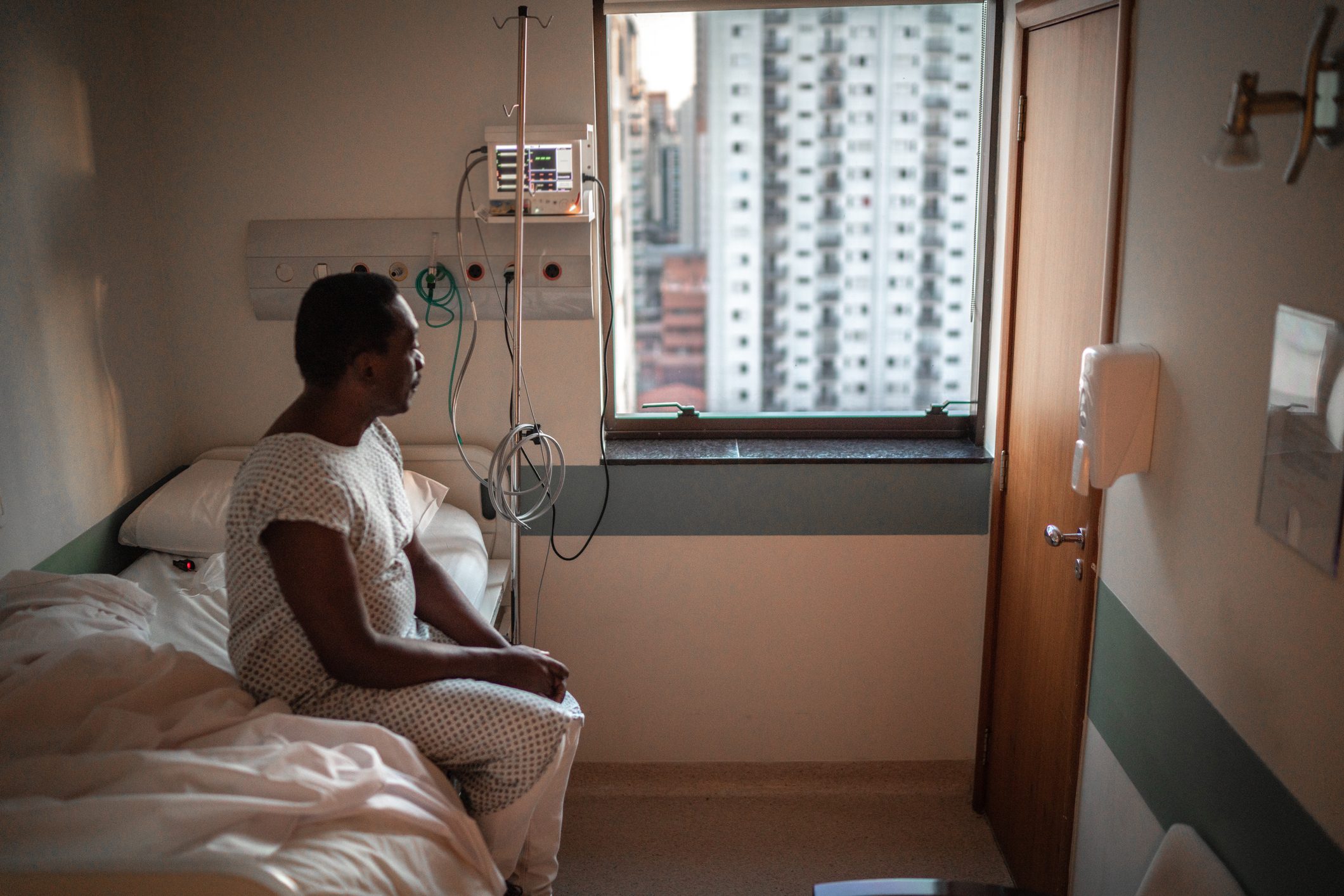 patient sits on hospital bed and looks out window