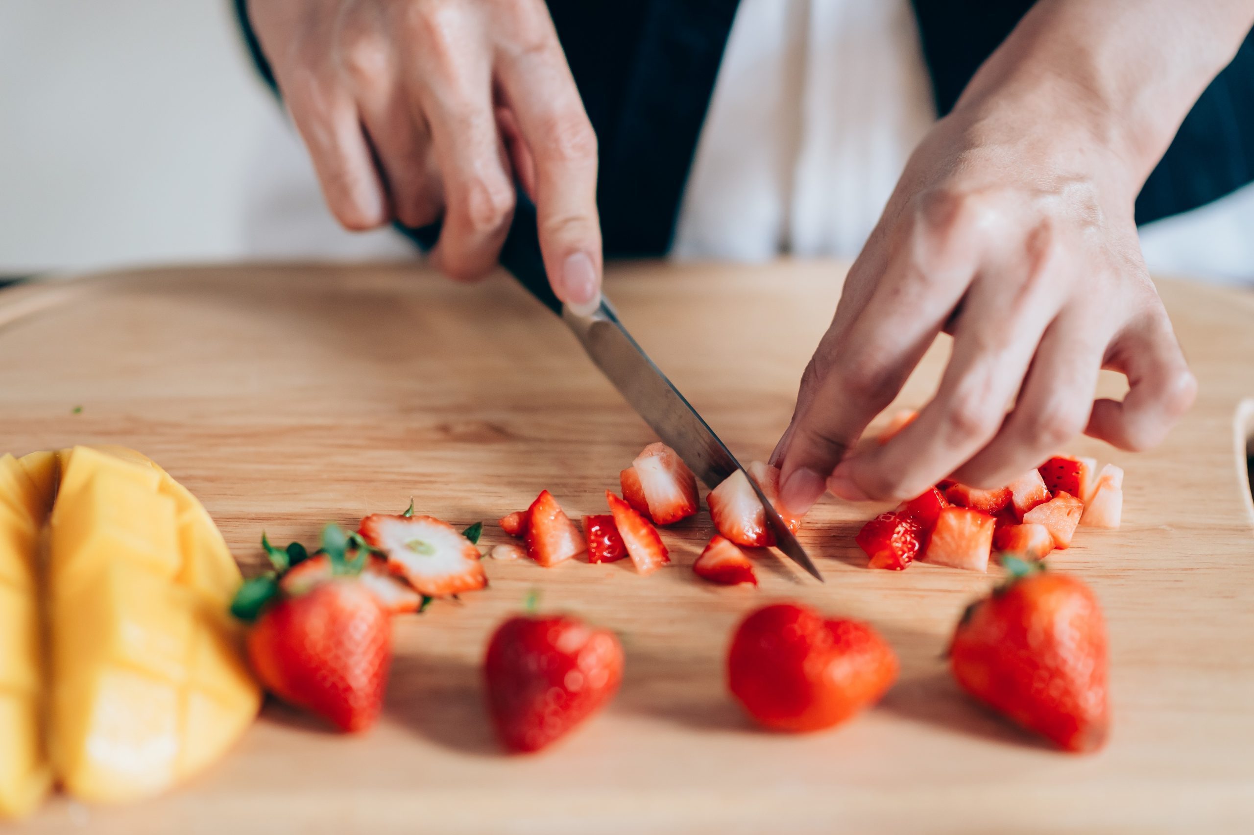 Chef Hand And Knife Slicing Fresh Strawberry On Wooden Cutting Board