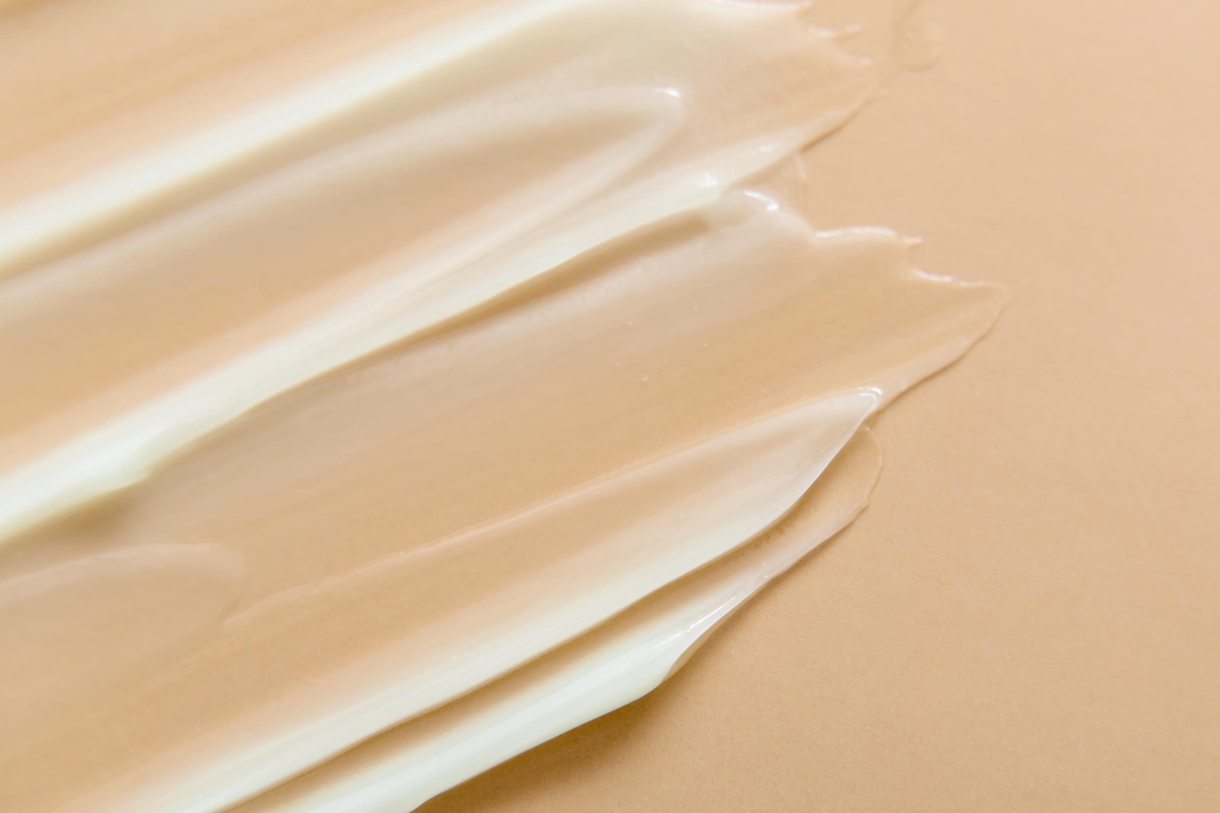 Liquid gel cream texture on beige background.