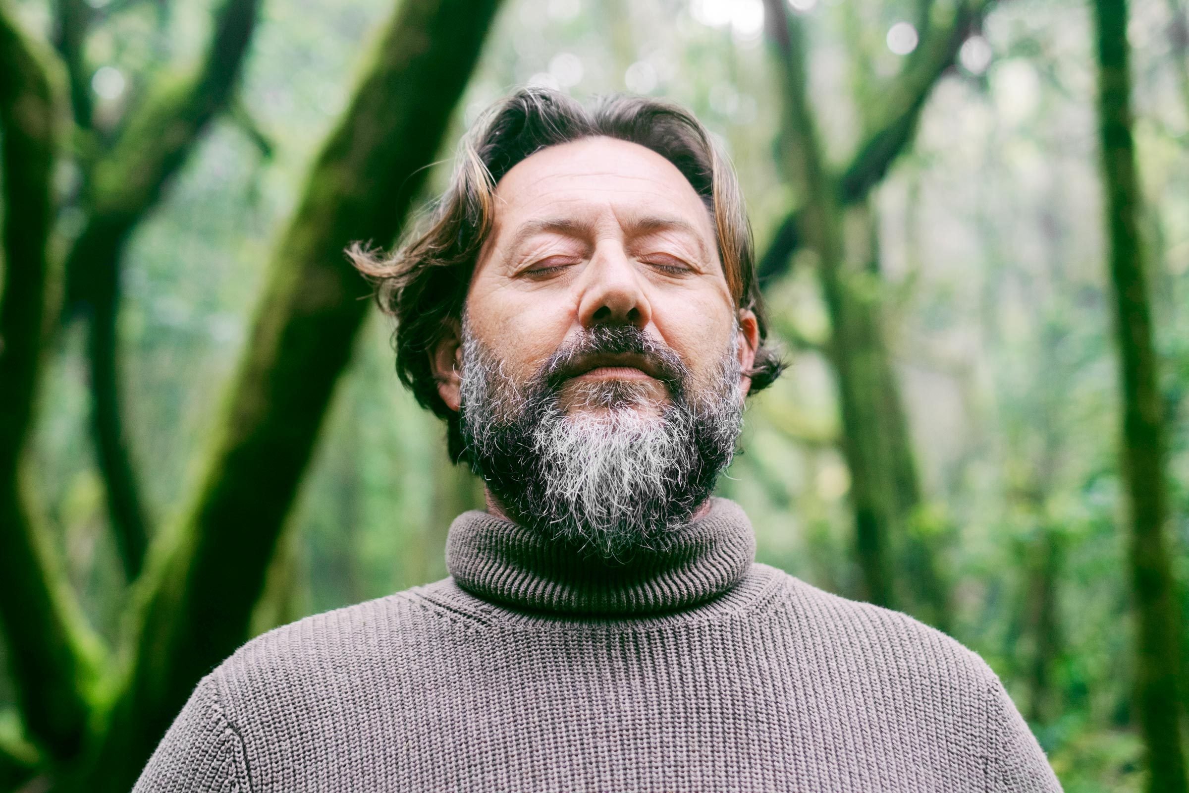 man in nature meditating and practicing deep breathing to reduce stress