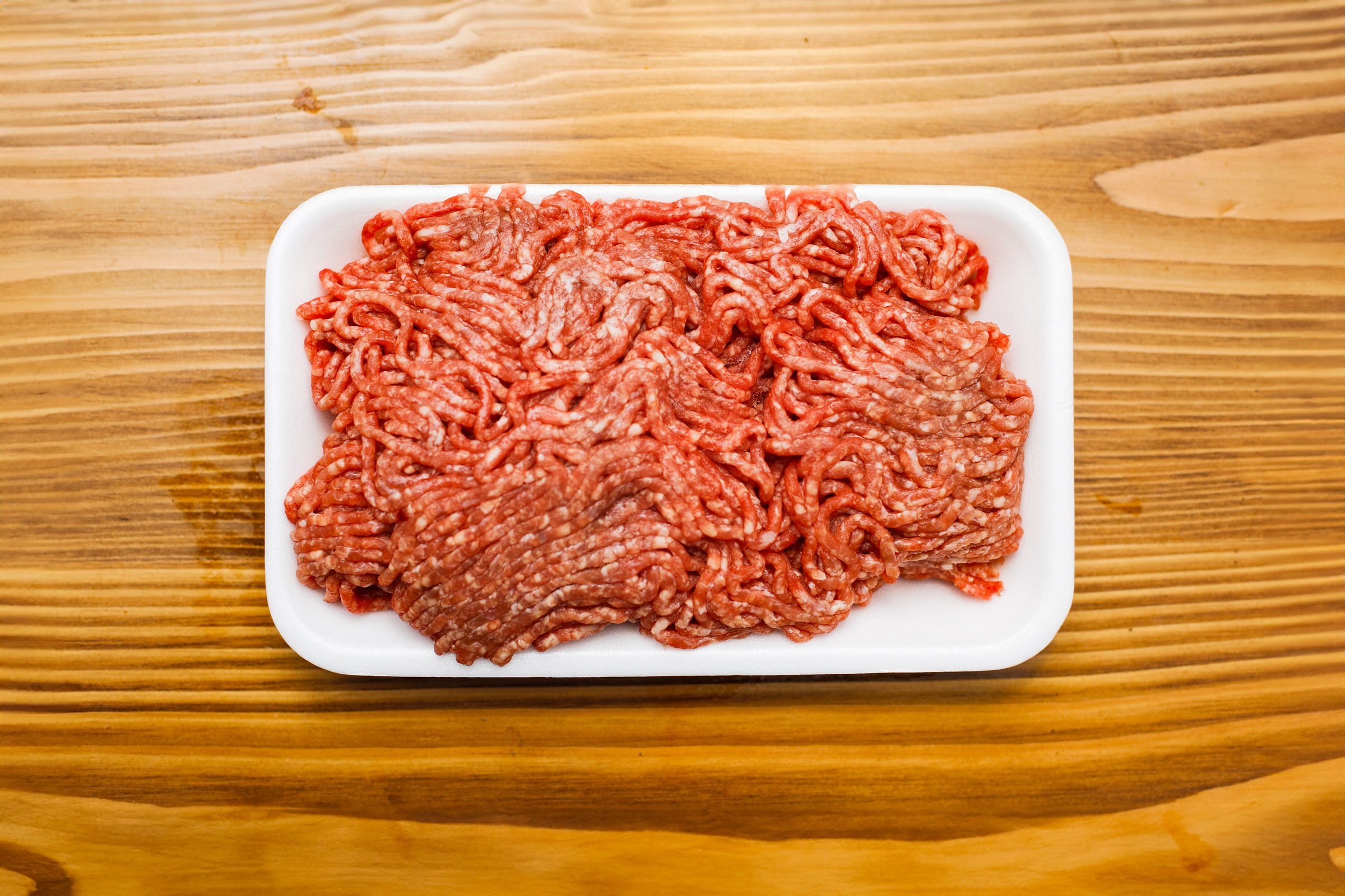 ground beef in white styrofoam tray on a wooden background