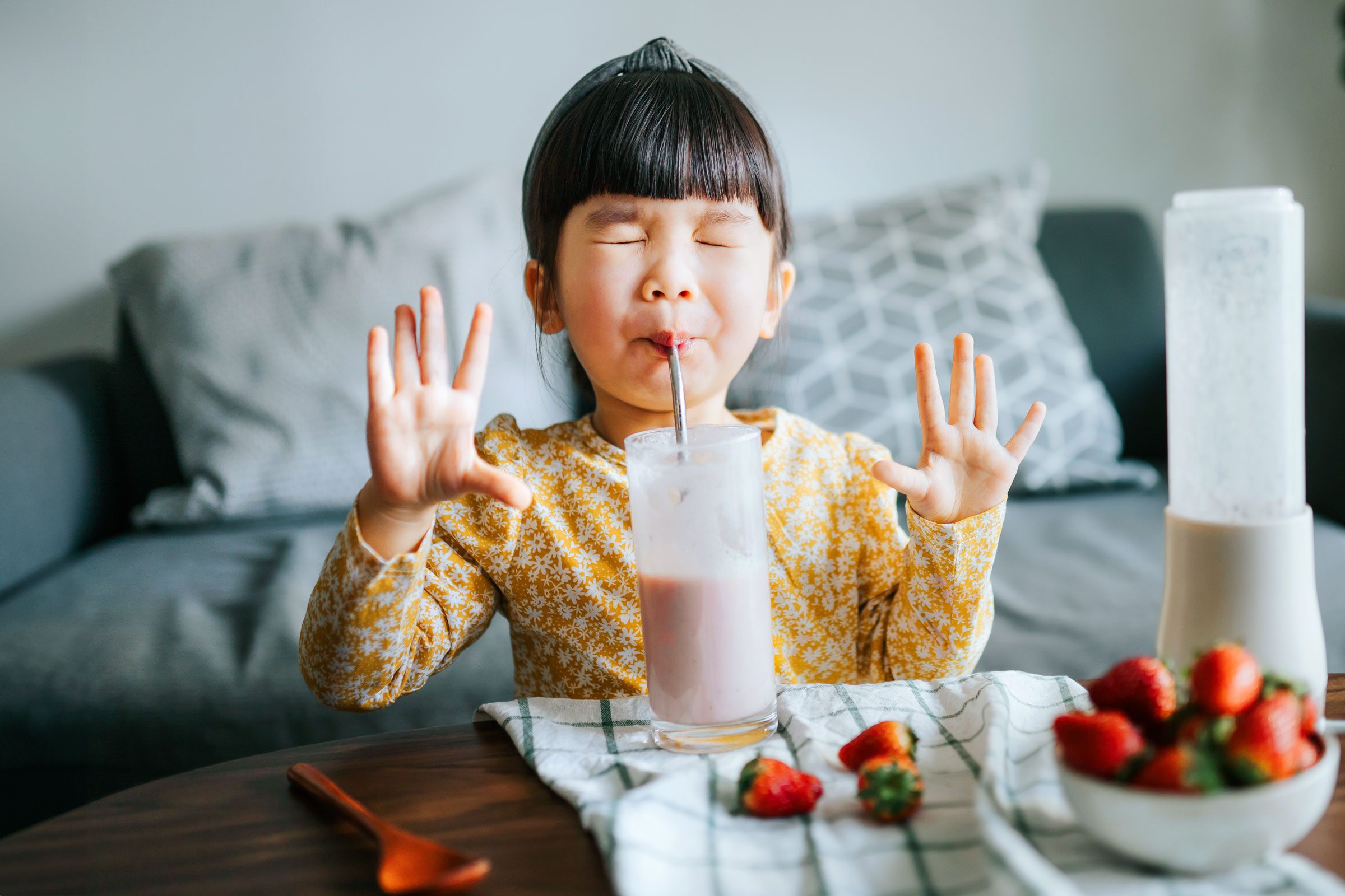 young girl drinking a smoothie and getting a brain freeze