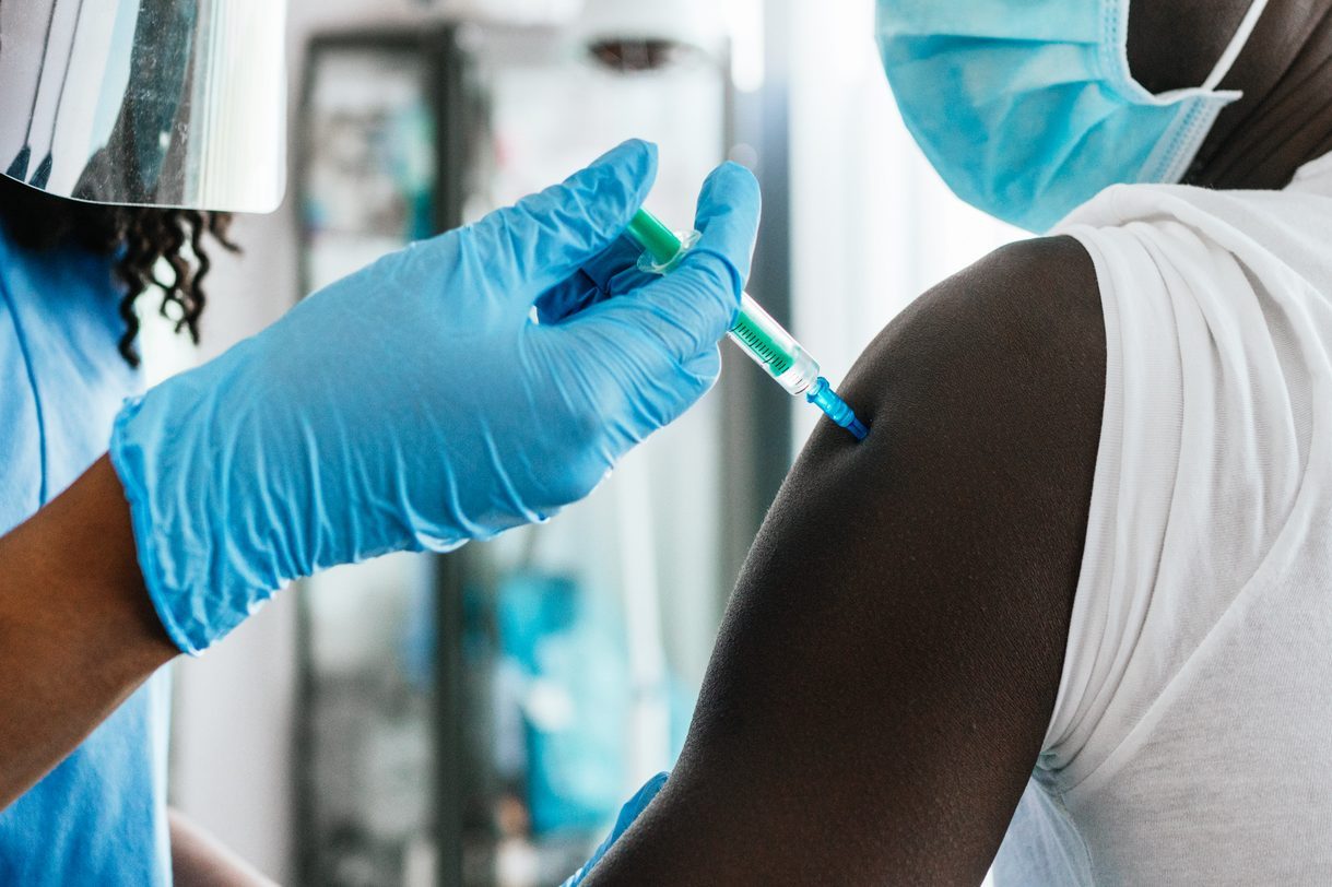 Close up view of an adult young man receiving a vaccine at a medical clinic