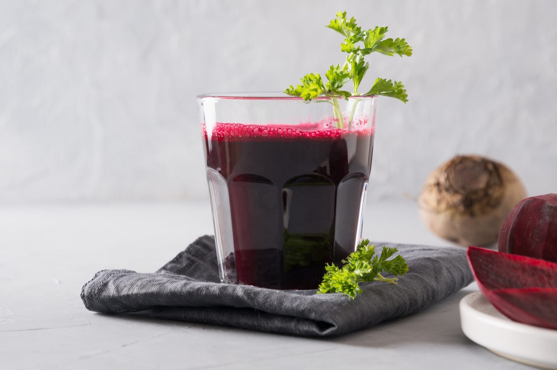 Glass of fresh beetroot juice garnish parsley on grey,Romania