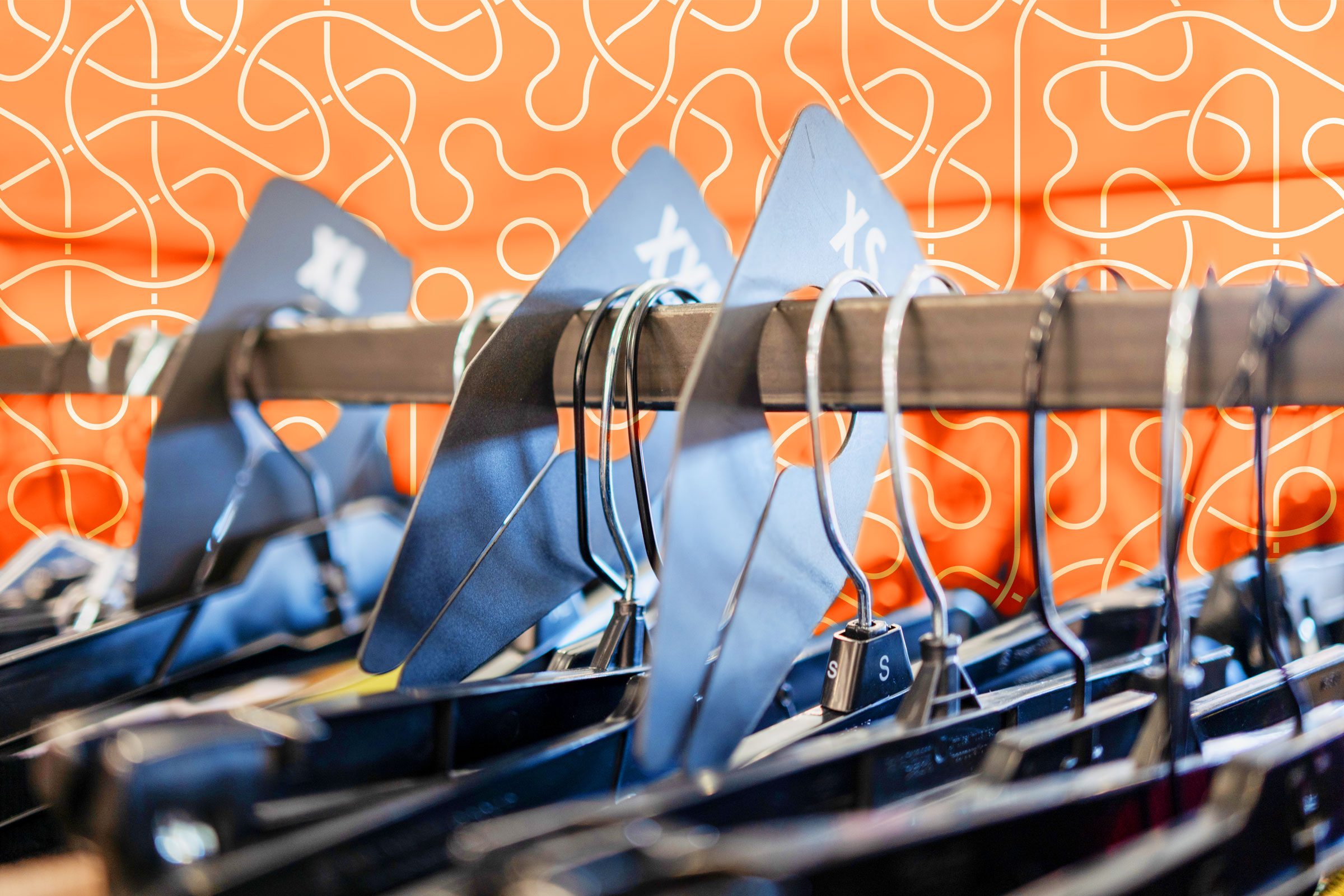 hangers with different sizes in a store with an orange swirly graphic background