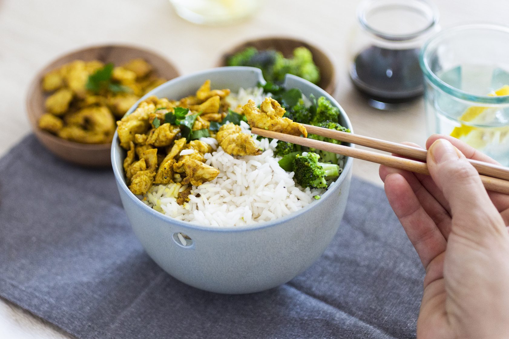 Curry chicken, broccoli and rice, woman with chopsticks