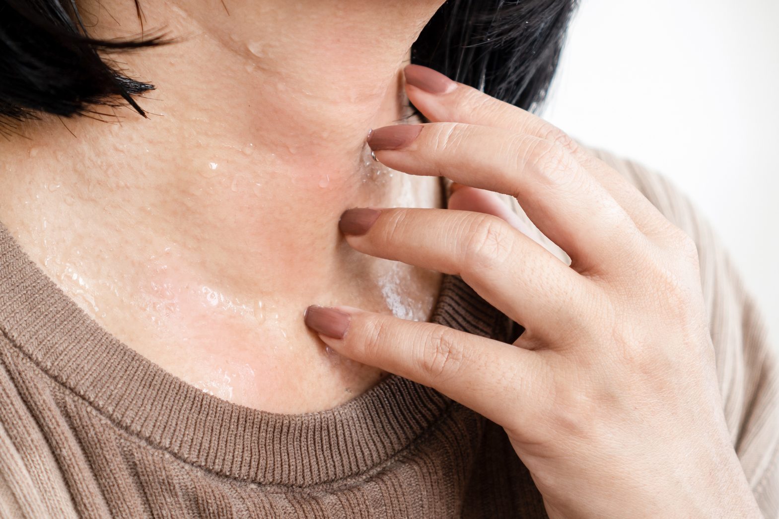 closeup woman's hand scratching itchy skin on her neck caused by allergic to sweat