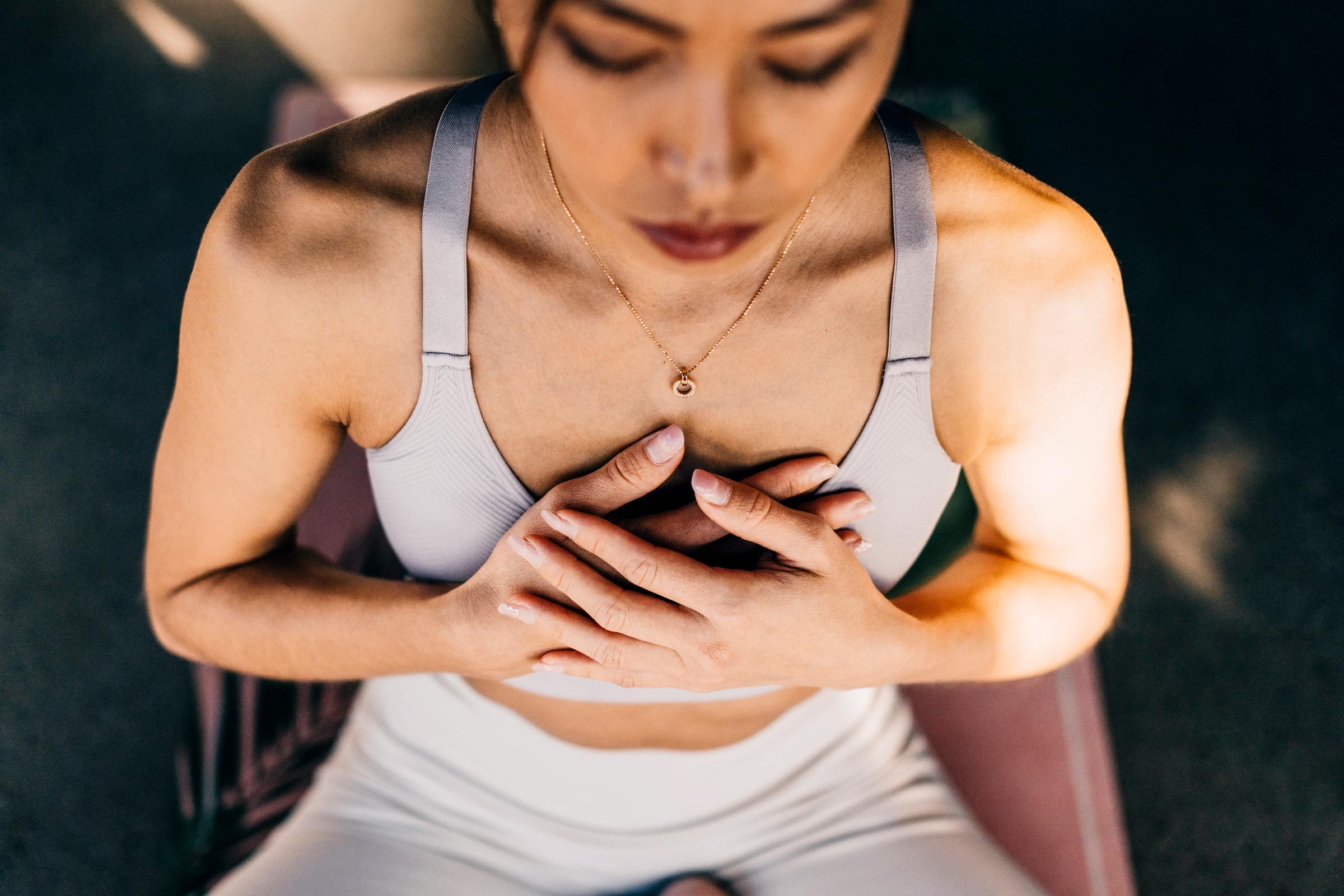 woman with anxiety is doing yoga or meditating is holding her chest while breathing