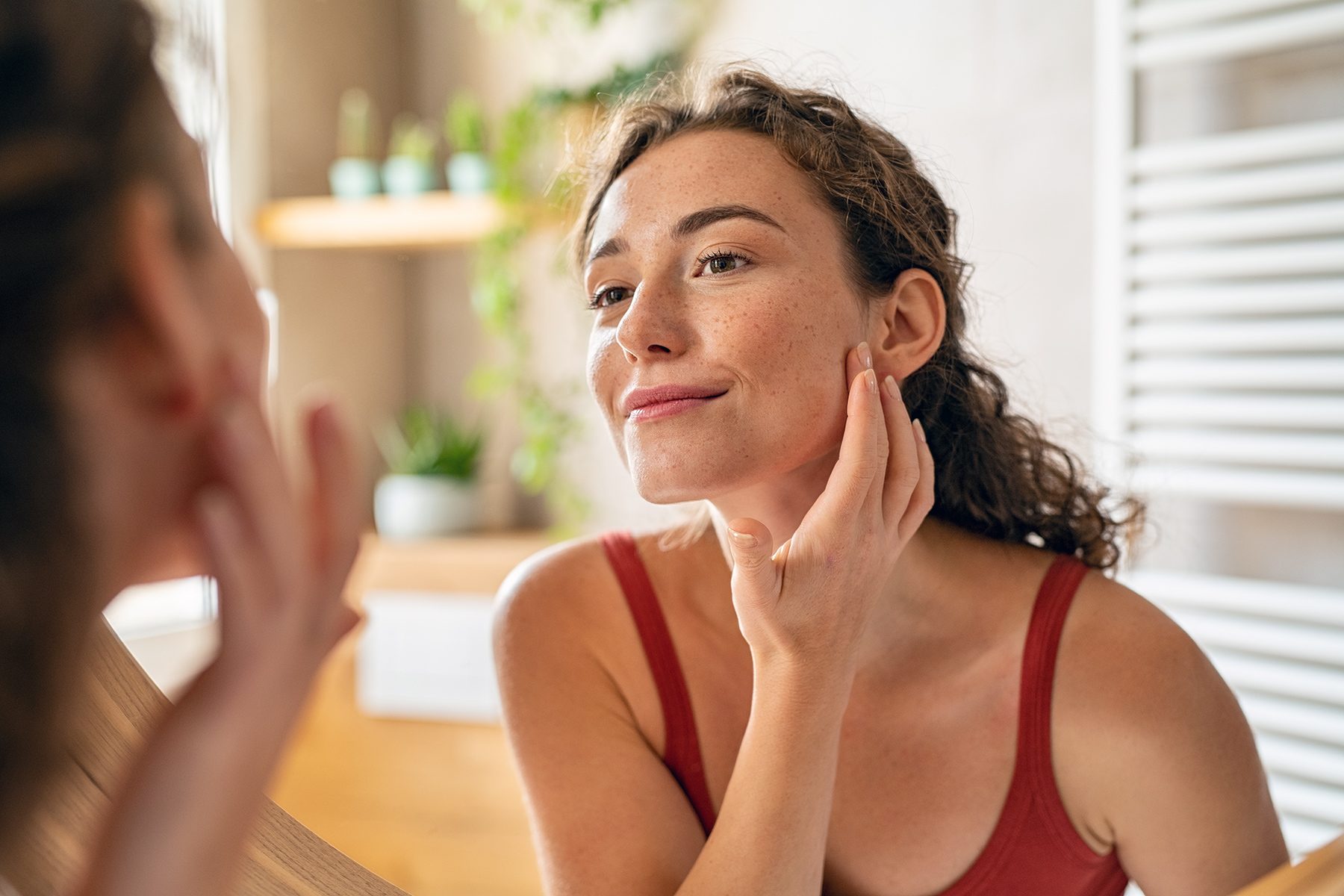 Young beauty woman checking her skin at mirror in the morning