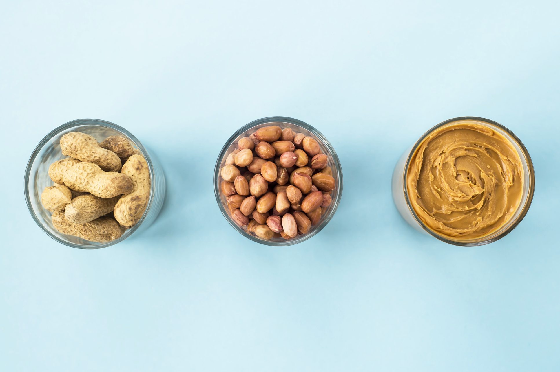 Three jars of peanut in a shell, peeled peas and vegan peanut butter. Cooking Natural Healthy Food Concept. Top view, flat lay