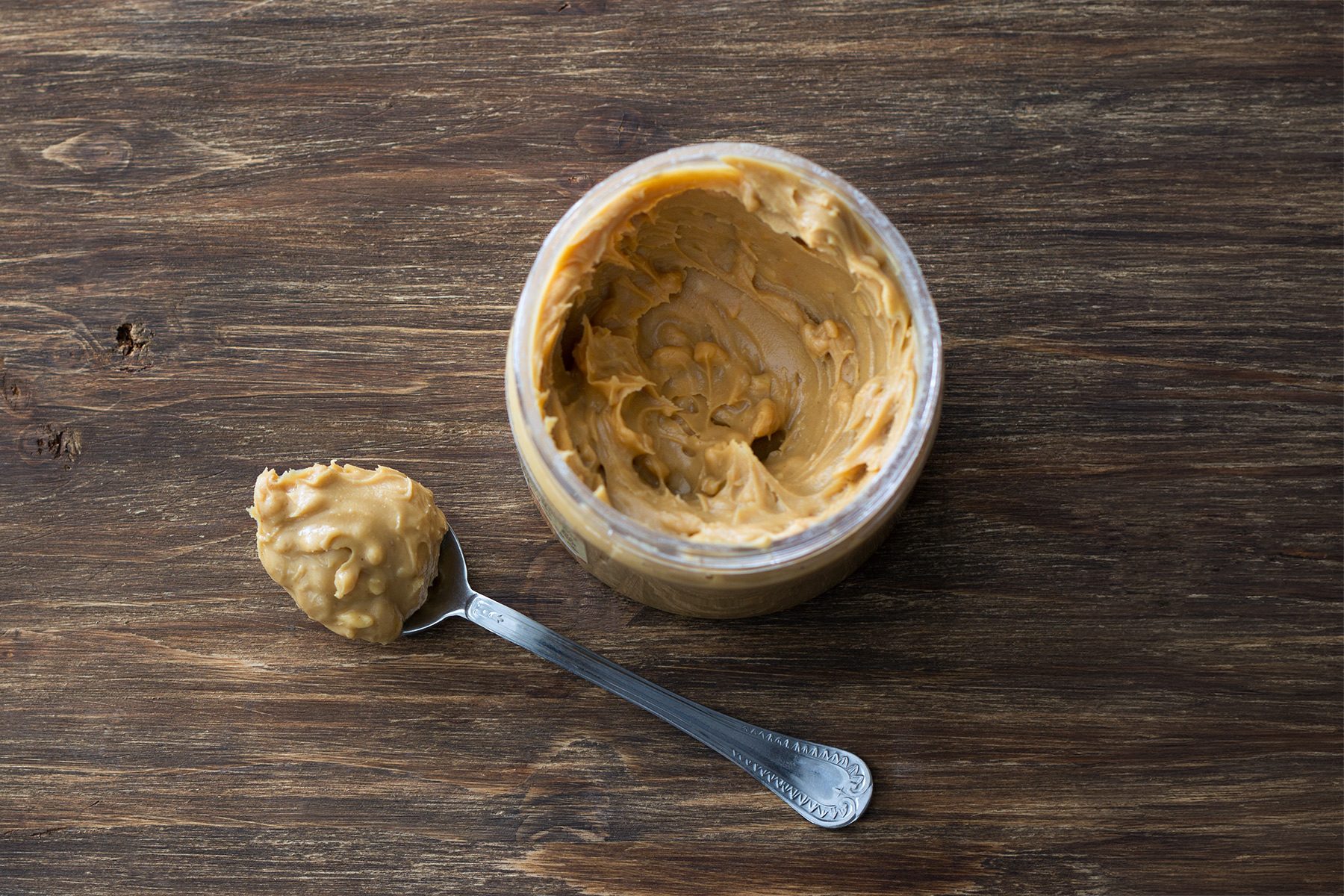 Jar with peanut butter on a wooden table, top view, free space