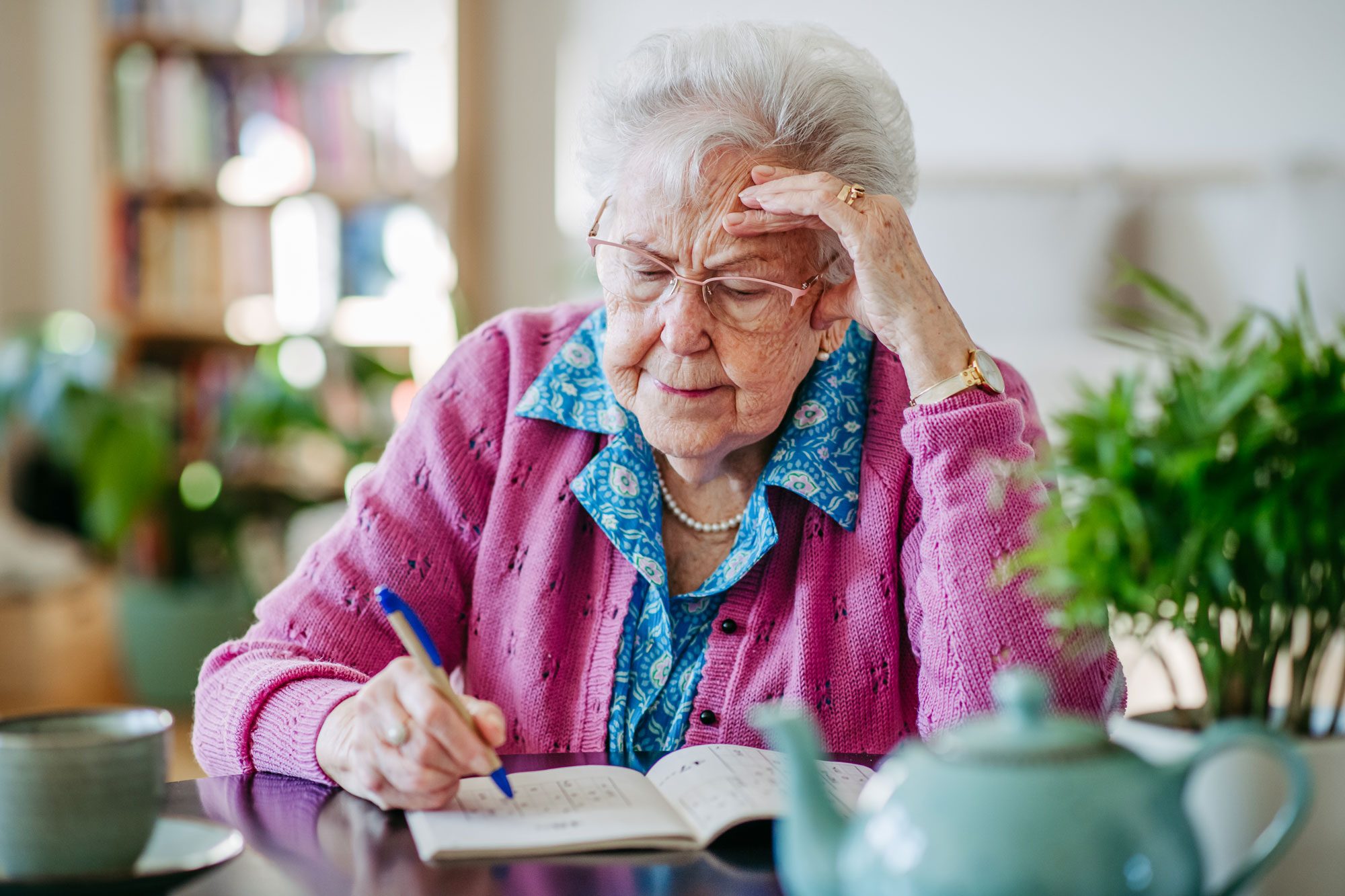 Elderly Woman Solving Sudoku Puzzles At Home