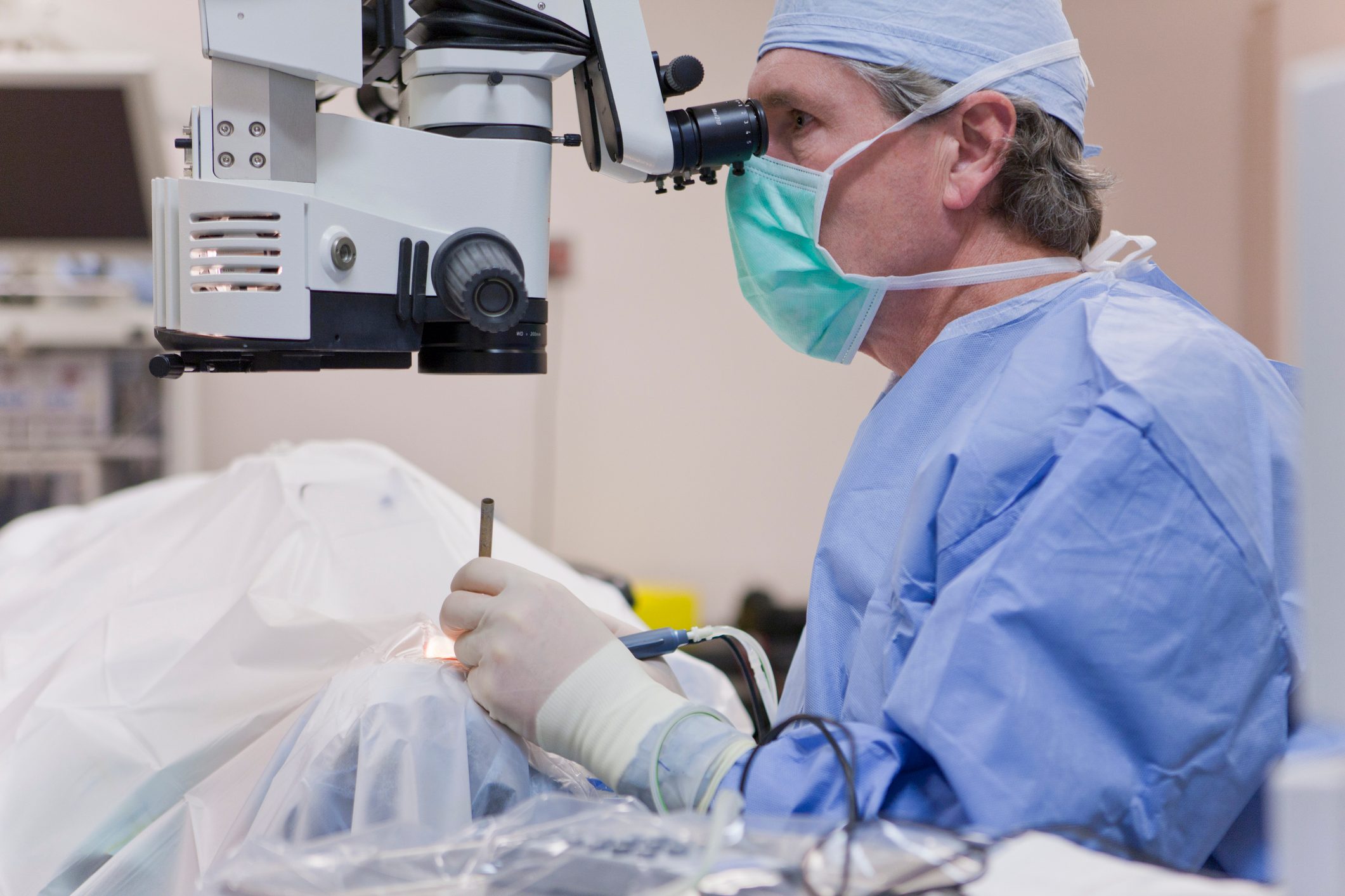 Doctor looking in microscope using a cracker instrument and phaco hand piece during cataract surgery