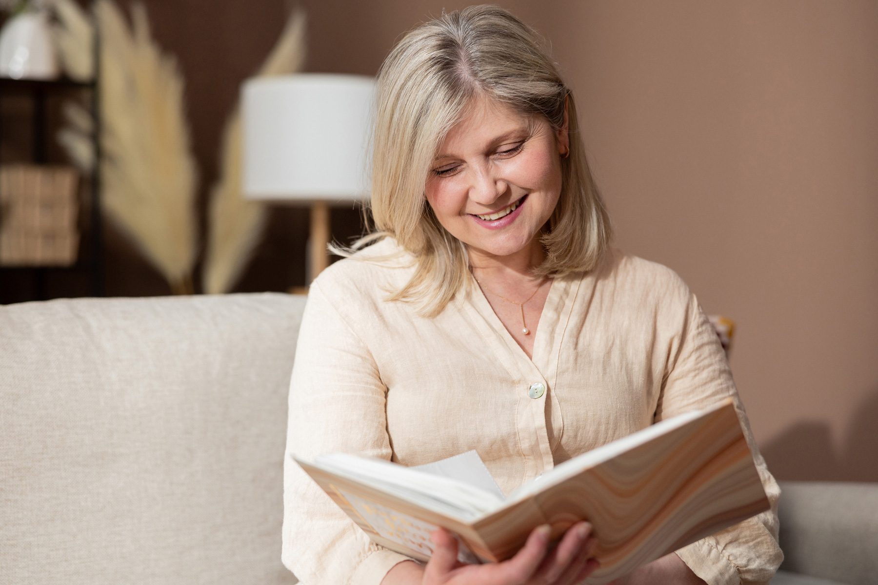 Mom looking at a photo book. A family tradition of printing photos and looking at them and reminiscing. An elderly woman smiles as she sees her children's photographs